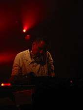 A man with headphones performs at DJ mixing desk.