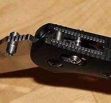 Close-up of pivot joint of a folding knife, showing locking barrel inserted through holes in the handle