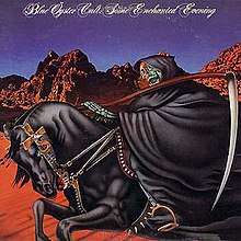 A skeleton in a black cloak carrying an axe rides a black horse in a desert with a dark blue sky behind them.