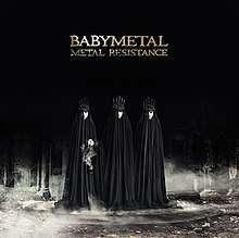 Three girls dressed in dark robes and five-pronged crowns stand in debris, in front of a black background. "Babymetal" appears in a gold font above them, with the words "Metal Resistance" right below it.