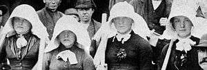 Four women wearing large white bonnets