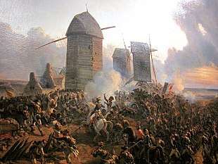 Painting shows scores of soldiers attacking from right to left while three windmills loom over them.