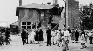 onlookers mill around, looking at the half-destroyed Bath School building