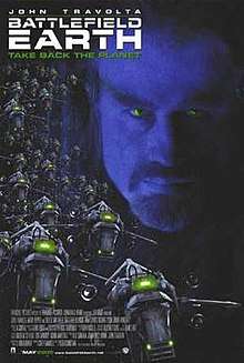 Movie poster which reads: John Travolta / Battlefield Earth / Take Back The Planet. A man's face with a goatee beard appears in the background, and alien spaceships in the foreground.