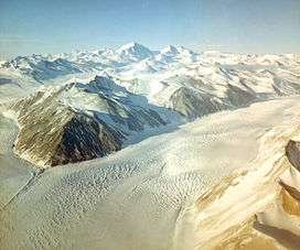  Aerial view: mountain ranges at top and bottom right of picture are separated by a broad ice river.