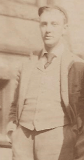 A grainy image of a man in a hat and a three-piece suit informally posing for a picture