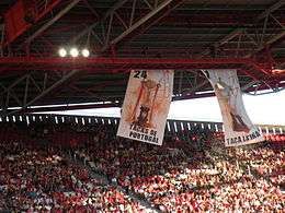 Grandstand with two large banners and fans wearing red and white