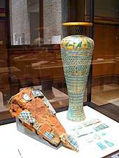 Tall vase covered in blue faience and gold motifs.