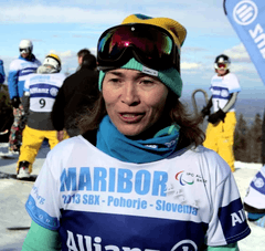 A woman standing, facing the camera, holding skis