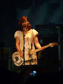 A woman performing live onstage with an electric guitar.