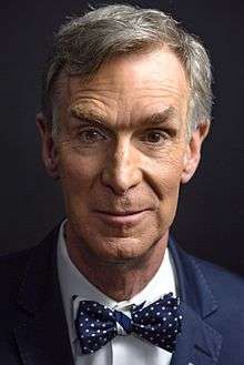 A close-up shot of Bill Nye's face, wearing one of his trademark bowties.