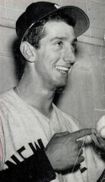 A candid shot of a young man in a baseball uniform, smiling and holding a baseball