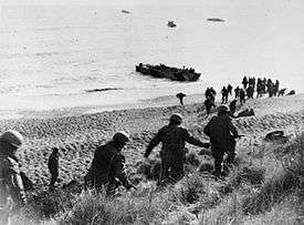 Men running down a cliff towards a waiting boat on the shore line