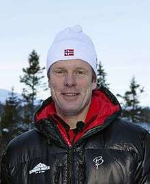 A man, standing, wearing a ski cap.