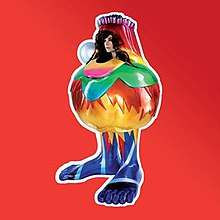 A kind of metal sculpture in the shape of a "fat" bottle with feet, decorated with many colours and flowers, in front of a red background. The sculpture has a big pearl on one of its sides and a hole that shows Björk's head.
