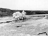 View of an explosion atop a dam in a flooding river