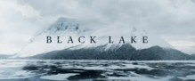 In the foreground, ice floats on the surface of a dark lake. In the background, snow caps the peaks of two mountains. The words Black Lake are superimposed in the centre.