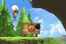 In-game screenshot of the Boy using the Blob as a parachute. The two are hovering over a ledge in a forested area with a large sign beneath them indicating the player should use the parachute transformation.