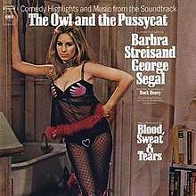 Streisand stands at the doorway to a bathroom wearing black lingerie.