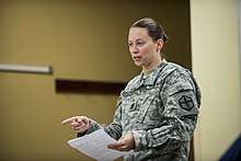 Raquel DiDomenico addresses an audience in uniform