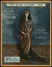 Sheet music cover showing a white woman with long, dark hair, dressed in a floor-length patterned gown and matching headpiece; her image is surrounded by text giving credits for the play and song.