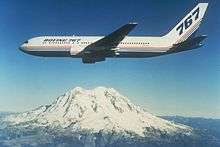 Boeing twin engine jetliner in flight near a snow-capped mountain