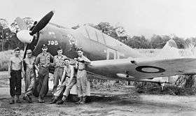 Six men stand around the nose of a radial-engined fighter plan