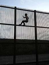 "Wildlife-friendly" border wall in Brownsville, Texas, which would allow wildlife to cross the border. A young man climbs the wall using horizontal beams for foot support.