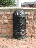 A black cast-iron half-round post with a domed top. Around one metre high. It has the year '1877' in white raised lettering. It also says 'CITY OF NOTTINGHAM' in capital letters which is accompanied with the coat of arms of the City of Nottingham, and the word 'BOUNDARY' in capital letters below that.