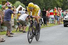 Bradley Wiggins riding a time trial bicycle wearing yellow cycling clothing