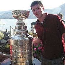 Brendan Burke standing next to the Stanley Cup.