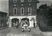 1930s fire engines leaving a brick firehouse