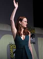 Brie Larson is seen waving, facing right