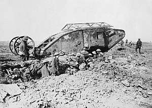 Early World War I tank, with soldiers in a trench next to it