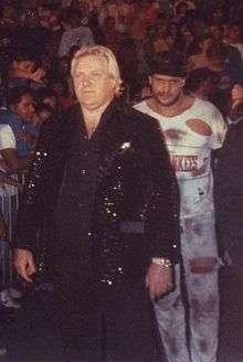 Bobby Heenan, dressed in a black sequin jacket, leads The Brooklyn Brawler to the ring in the late 1980s