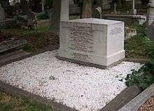 A cubical white marble work of masonry, approximately three feet wide, 18 inches deep and two feet high, inscribed with names of members of the Brunel family, surrounded by marble chippings