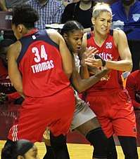 Thomas and Delle Donne wearing bright red uniforms attempt to squeeze Brunson out as she emerges between them