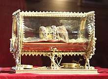 A mumified hand, with a strip decorated with pearls on it, in a gilded box