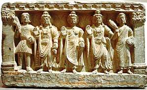 stone statue group, a Buddhist triad depicting, left to right, a Kushan, the future buddha Maitreya, Gautama Buddha, the bodhisattva Avalokiteśvara, and a Buddhist monk. 2nd–3rd century. Guimet Museum