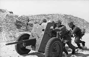 a black and white photograph of soldiers pushing a light artillery piece