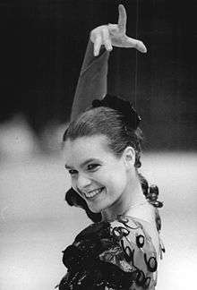 A young smiling woman wearing a traditional Spanish flamenco dress and head gear, and executing the typical flamenco posture.