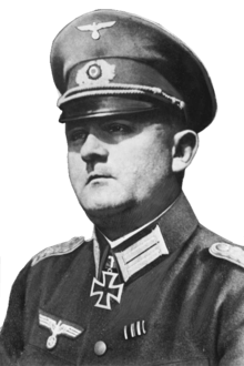 A man wearing a peaked cap and military uniform with an Iron Cross displayed at the front of his uniform collar.
