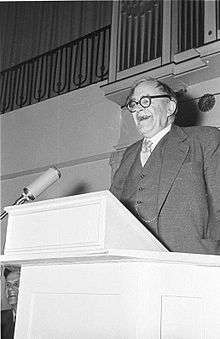 black and white photo of Barth laughing while speaking standing at a podium
