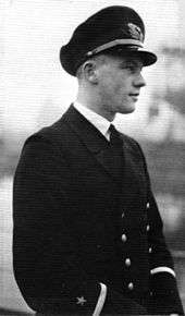 A black-and-white photograph of a man in semi profile wearing a dark military uniform and peaked cap.
