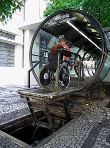 A special lift raises a wheelchair and its occupant to the platform of a bus stop