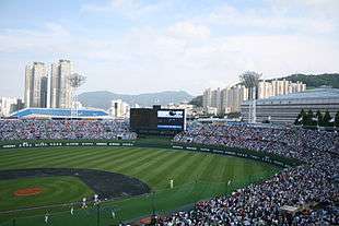 An open roof crowded baseball stadium with a match in progress.