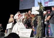 Photograph of people on stage in costumes, holding their prizes.