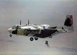 Photograph showing a CASA C-212 of the Chilean Air Force, with a parachutist jumping from the rear of the aircraft
