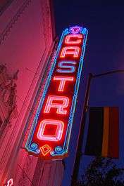 Seen from below, a neon sign that reads "CASTRO" in vertical letters is lit against a night sky.