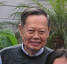 An old man, wearing a pullover is smiling.